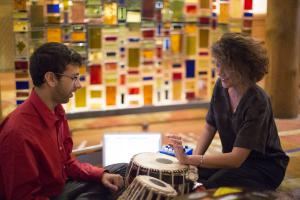 Two individuals playing an electronic drum
